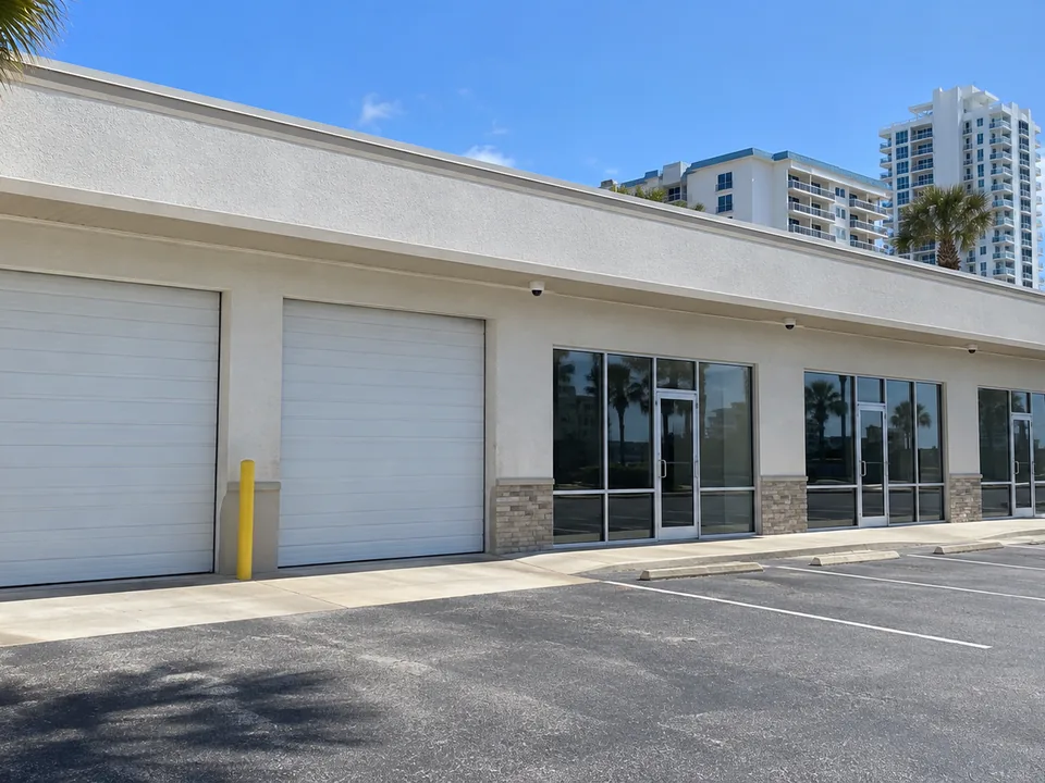Auto-service and retail strip along a South Daytona highway with white dome cameras flush under the eave