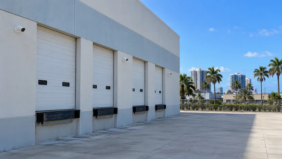 Warehouse loading docks with white bullet cameras on round wall mounts covering the truck yard